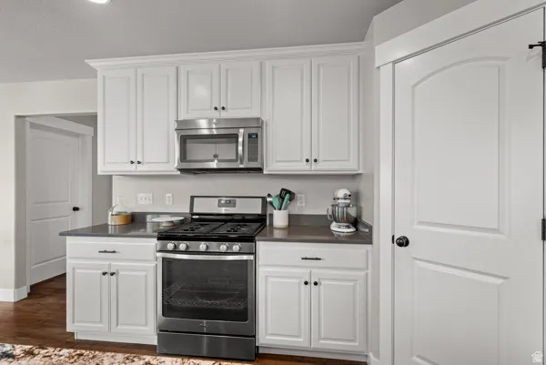 Modern kitchen featuring white shaker cabinetry, dark countertops, a stainless steel gas range, and an over-the-range microwave