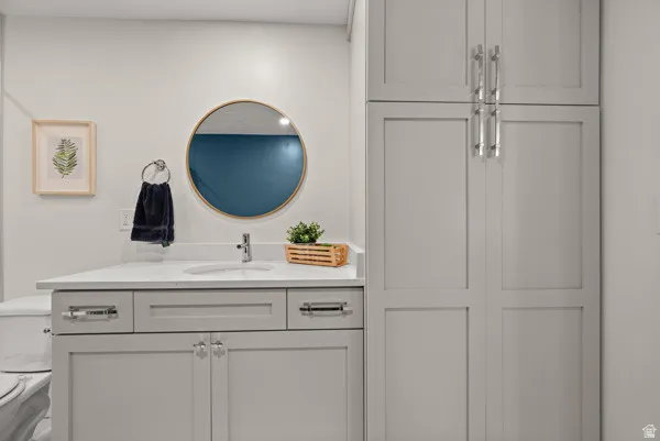 Bathroom vanity featuring a light gray shaker-style cabinet, white countertop, and an undermount sink