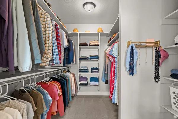Expansive walk-in closet featuring built-in shelving, multiple hanging rods, and integrated wall storage