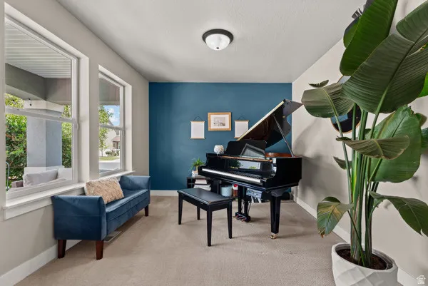 Inviting interior space featuring a distinct accent wall, neutral wall paint, two large windows, a ceiling-mounted light fixture, and carpet flooring