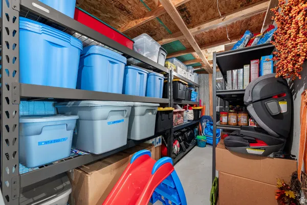 Dedicated storage room featuring multiple levels of industrial shelving and exposed ceiling joists