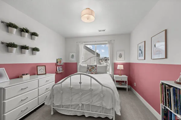 Bedroom featuring two-tone wall treatment, carpet flooring, window with white trim, and a ceiling-mounted light fixture