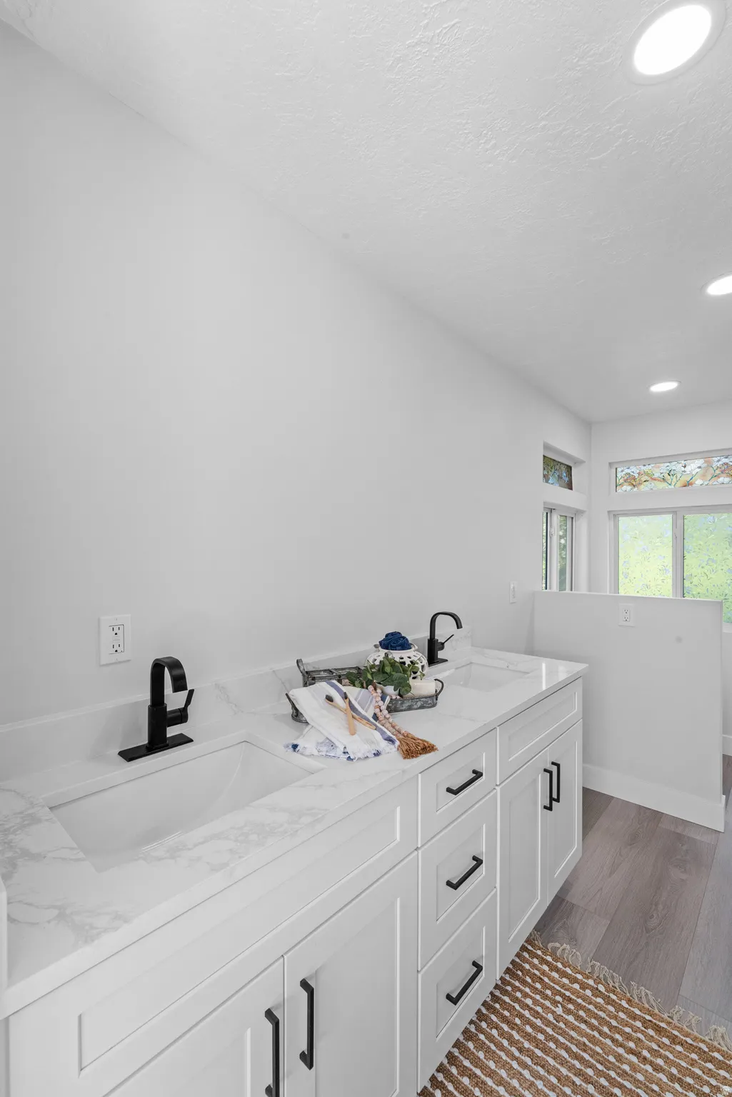 Dual vanity featuring white shaker-style cabinetry, white countertops with integrated sinks, and matte black fixtures
