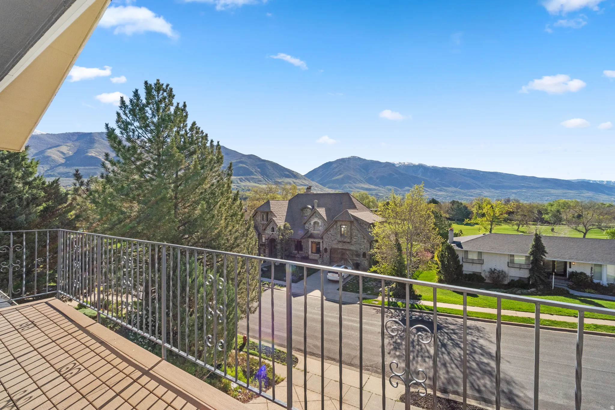Balcony with decorative metal railing and wood-finish flooring, offering expansive mountain scenery