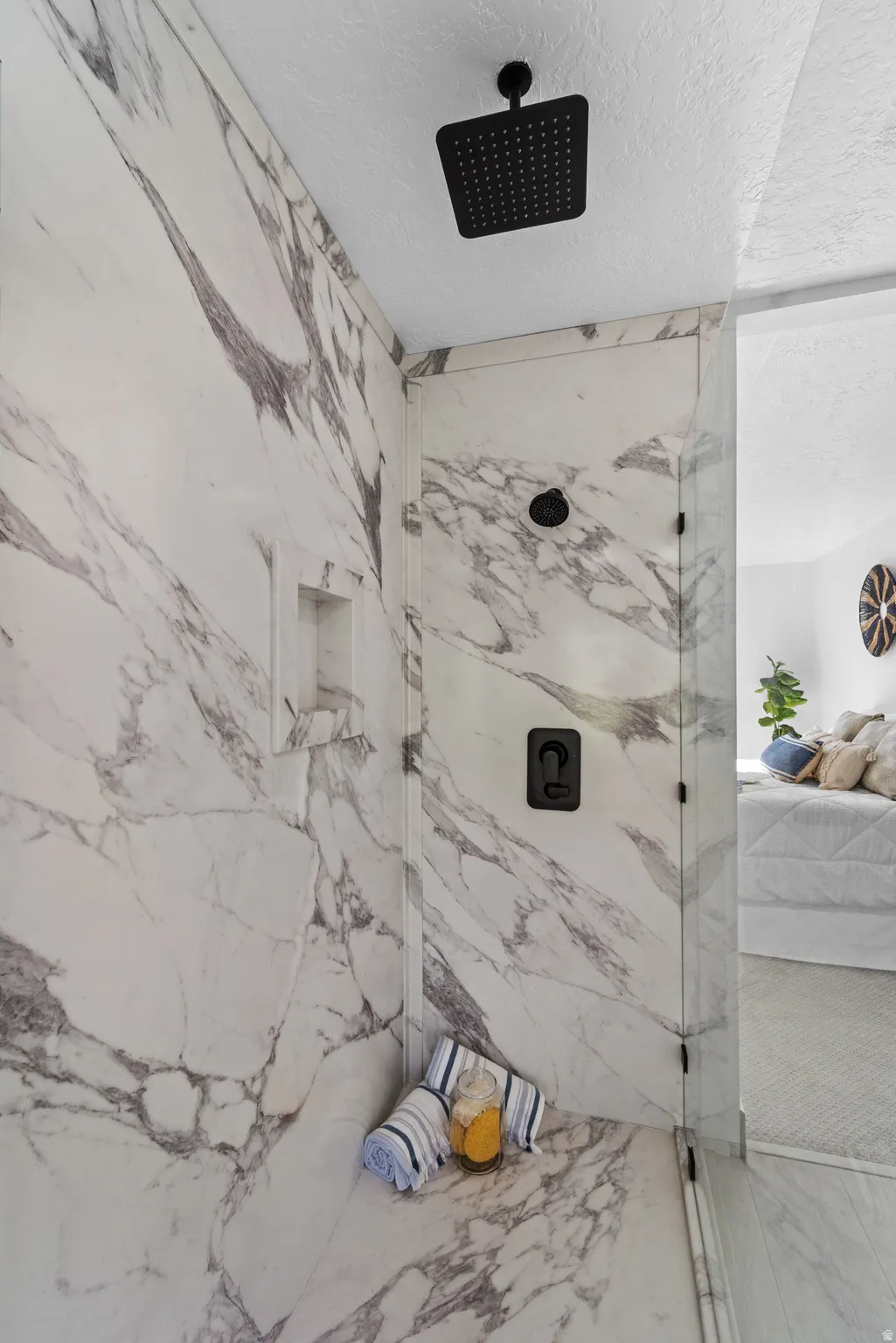 Walk-in shower featuring marble-look paneling, a recessed niche, a built-in bench, and matte black fixtures