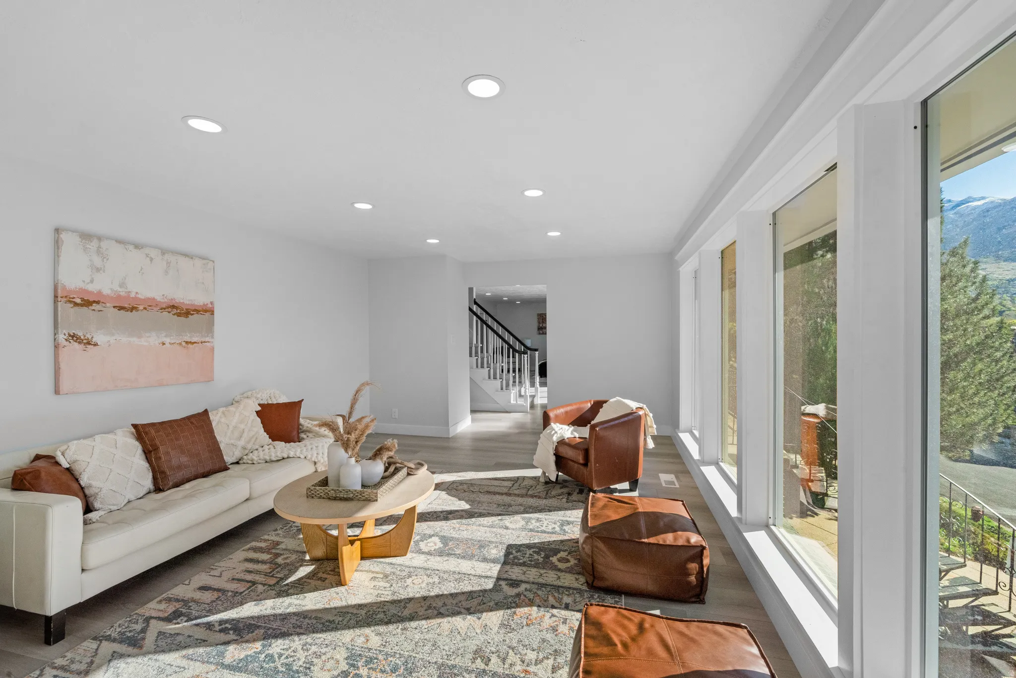 Living area featuring light wood-finish flooring, recessed lighting, and a prominent wall of windows