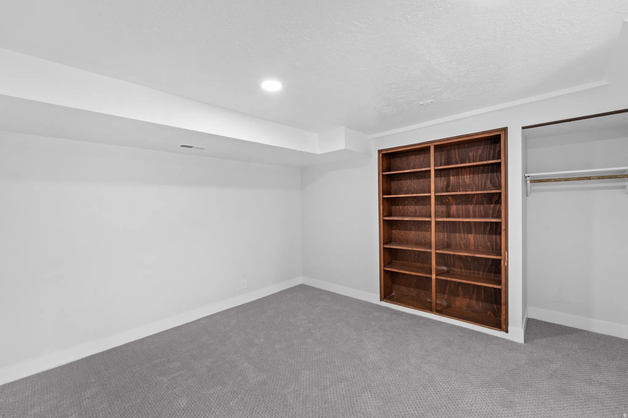 Room featuring built-in wood shelving and gray carpet flooring