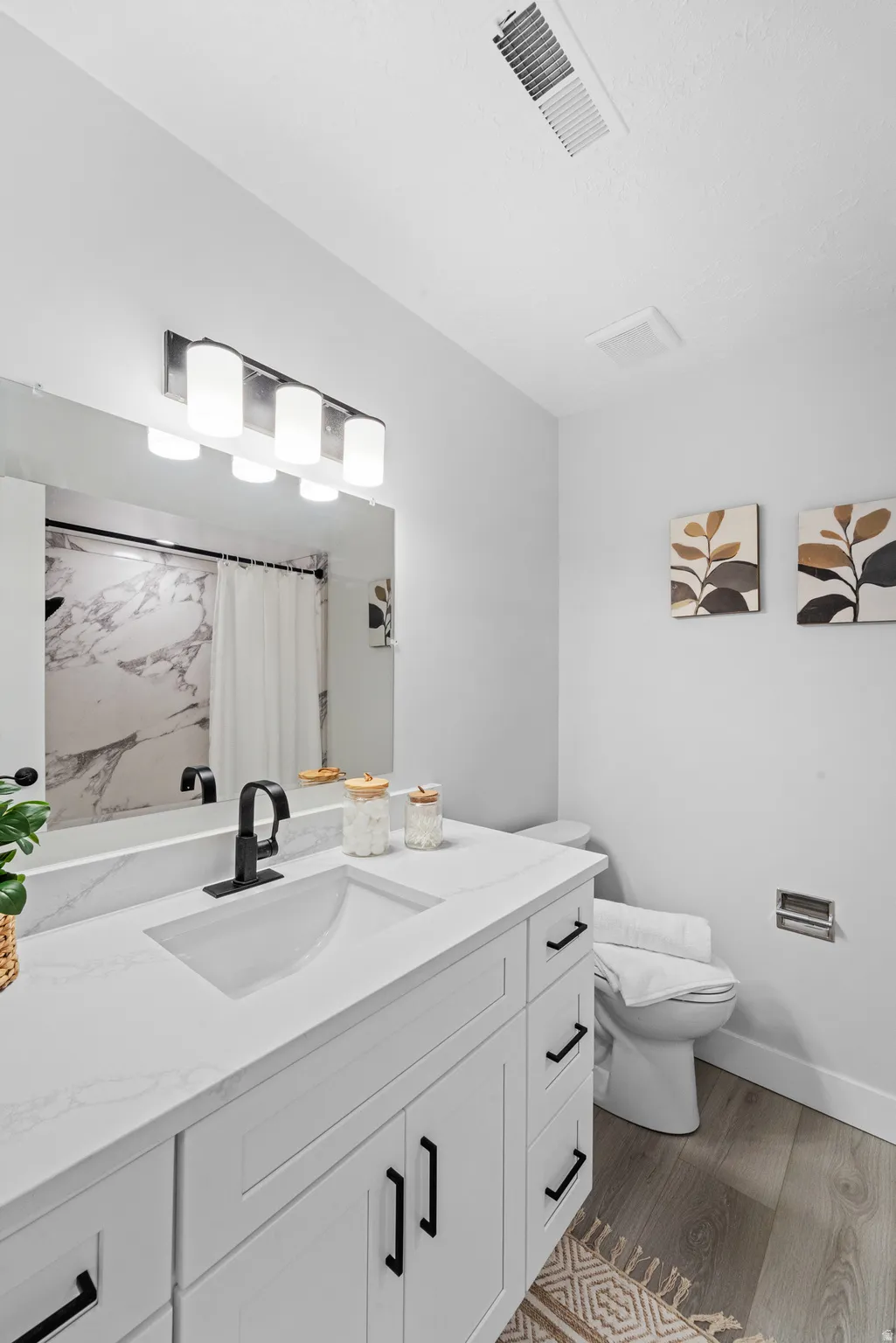 Modern bathroom featuring a white vanity with integrated sink, matte black faucet, and quartz-finish countertop