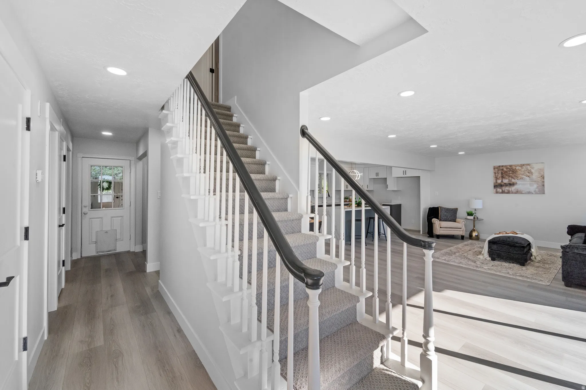 Carpeted staircase with dark handrail and white balusters