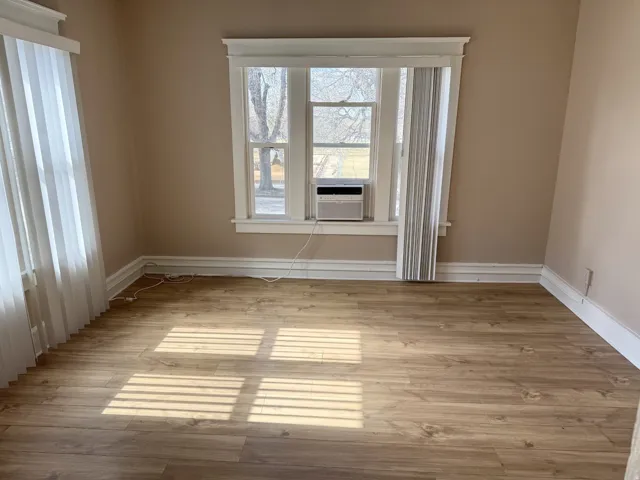 Room featuring wood-finish flooring, neutral wall paint, and white trim