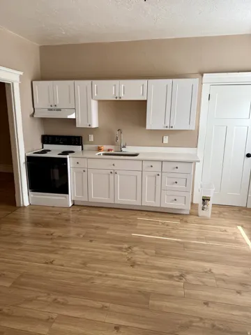 Kitchen featuring white shaker cabinetry, light-toned countertops, and a stainless steel sink with a gooseneck faucet