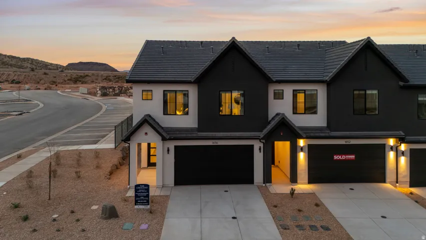 All Photos are of a similar model and finishes.Modern townhome exterior featuring contemporary design, dark siding, light stucco accents, two-car garage, and dark roof shingles