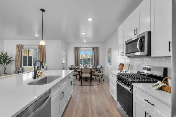 Modern kitchen featuring white shaker cabinetry, stainless steel appliances, a gas range, a single basin sink with a matte black faucet, and white countertops
