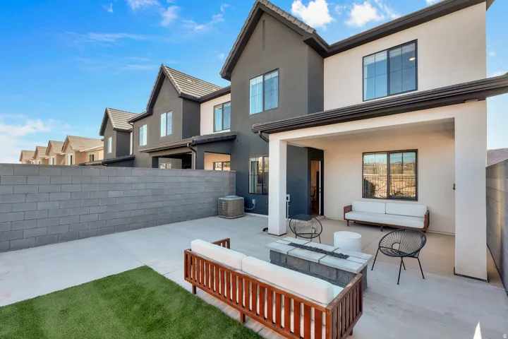 Private backyard featuring a concrete patio, artificial turf area, and a block privacy wall