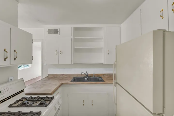 Kitchen featuring white cabinetry, a built-in range, a double basin sink, and a refrigerator