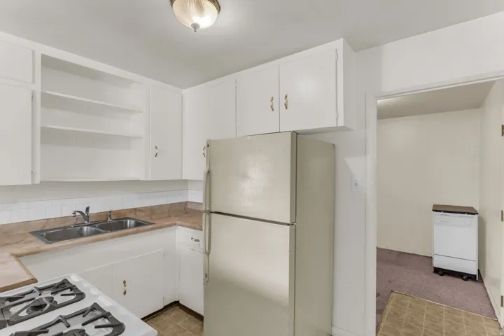 Kitchen featuring white cabinetry, a double basin stainless steel sink, and a gas range