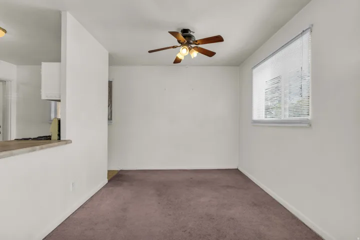 Spacious room featuring neutral carpeting and a ceiling fan with light fixture