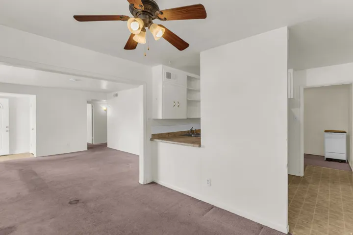 Open concept living area with purple carpeting and a ceiling fan with light fixture