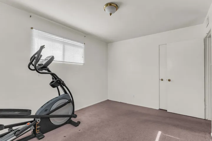 Room featuring a flush-mount ceiling light, white walls, and a window with horizontal blinds