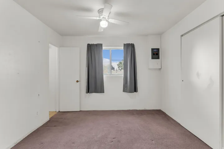 Interior room featuring a ceiling fan, central window, and neutral wall tones
