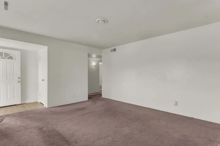 Spacious room featuring neutral painted walls, ceiling-mounted lighting, and purple carpet flooring