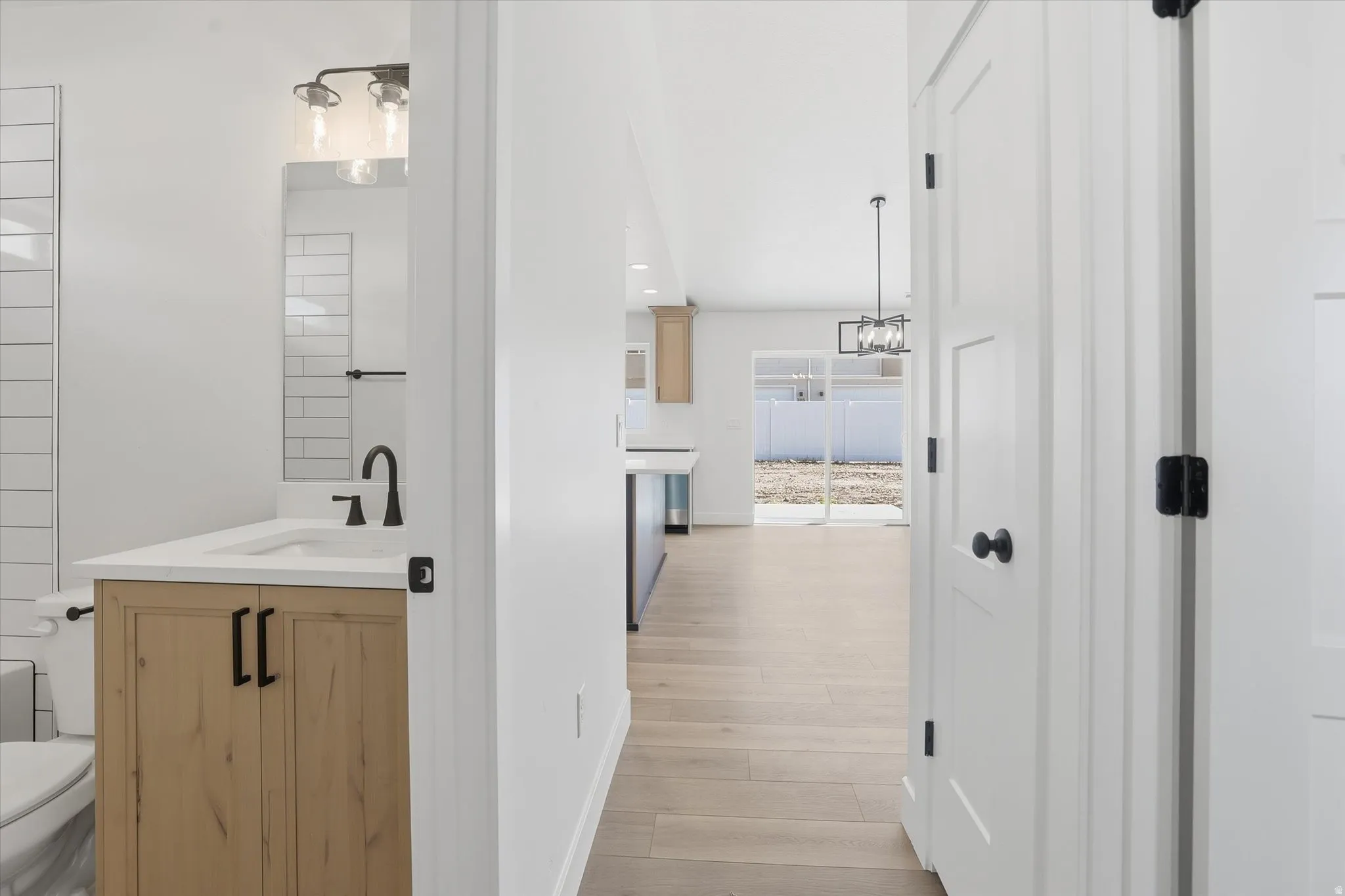 Bathroom vanity with light wood-finish cabinetry and black hardware