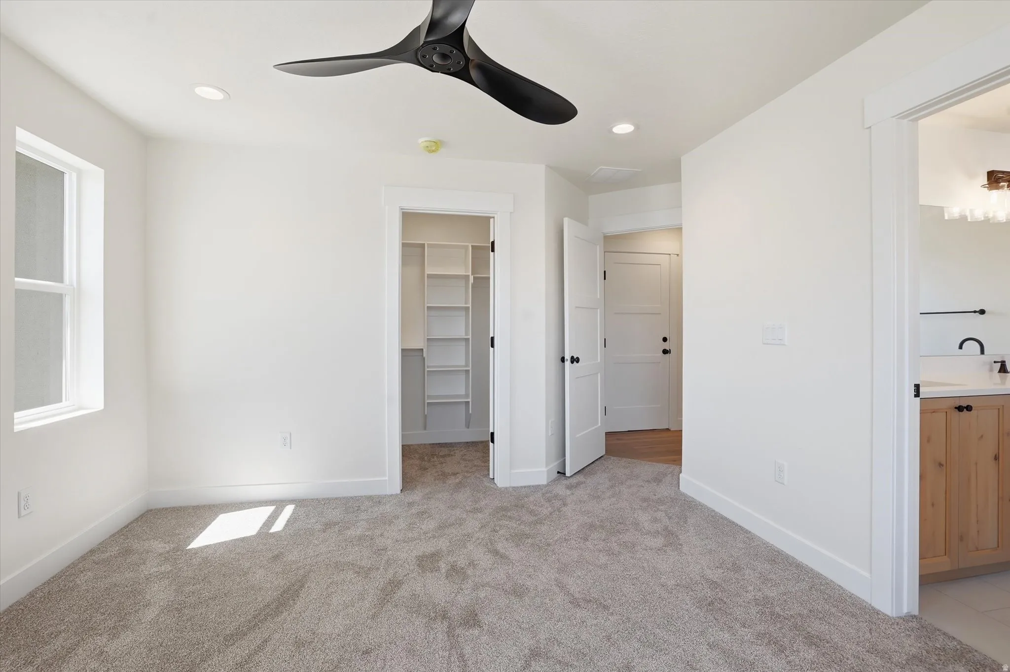 Carpeted room with a black ceiling fan, recessed lighting, and a window