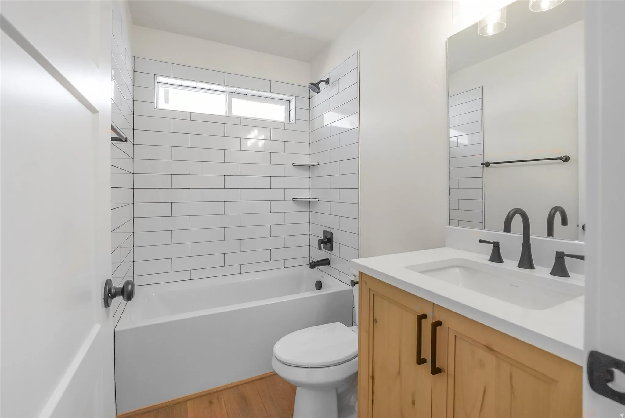 Bathroom featuring a white subway tile shower surround with integrated shelving and a transom window