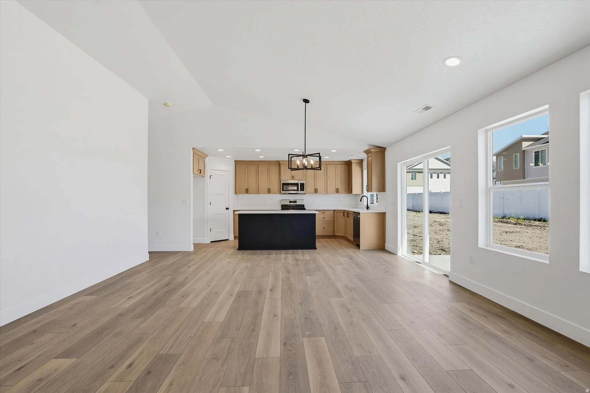 Open-concept living space featuring wood-finish flooring, vaulted ceilings, and recessed lighting