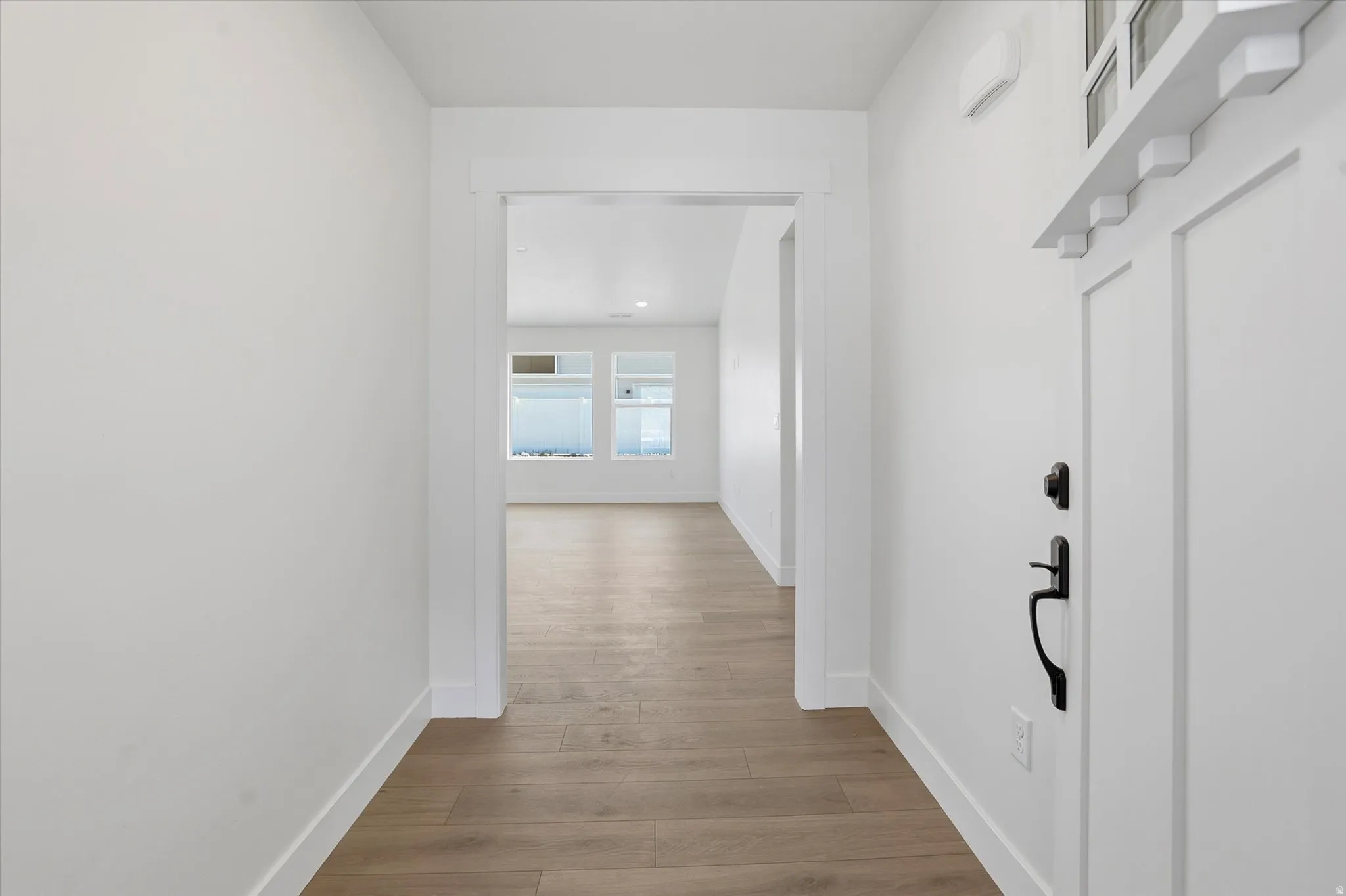 Entryway featuring wood-finish flooring, white trim, and a white paneled door with black hardware