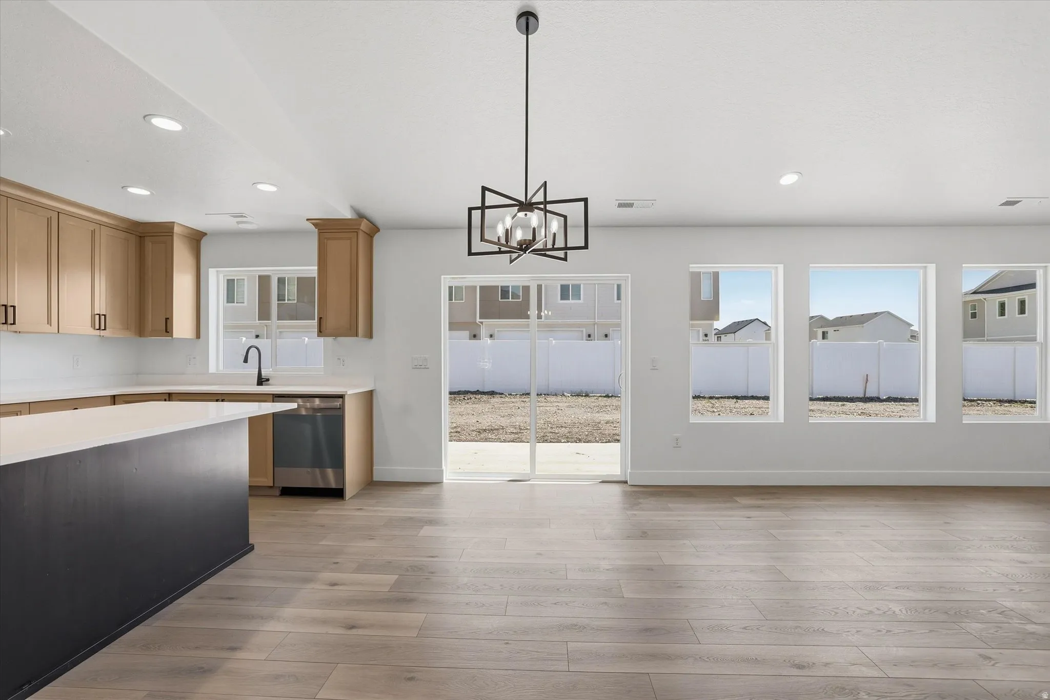 Open-concept living area featuring light wood-finish flooring, a contemporary chandelier, and recessed lighting