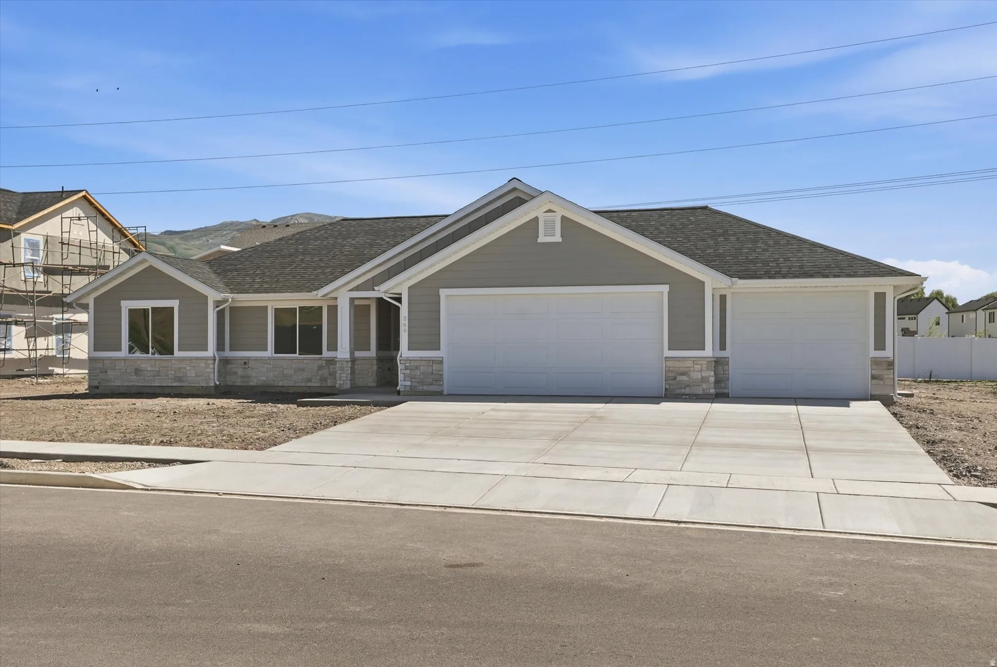 Contemporary ranch-style residence featuring light grey siding and stone veneer accents