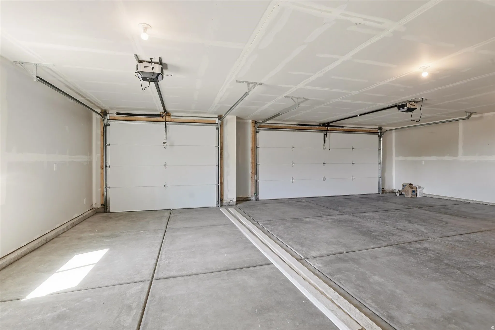 Two-car garage featuring concrete flooring, automatic garage door openers, and ceiling-mounted light fixtures