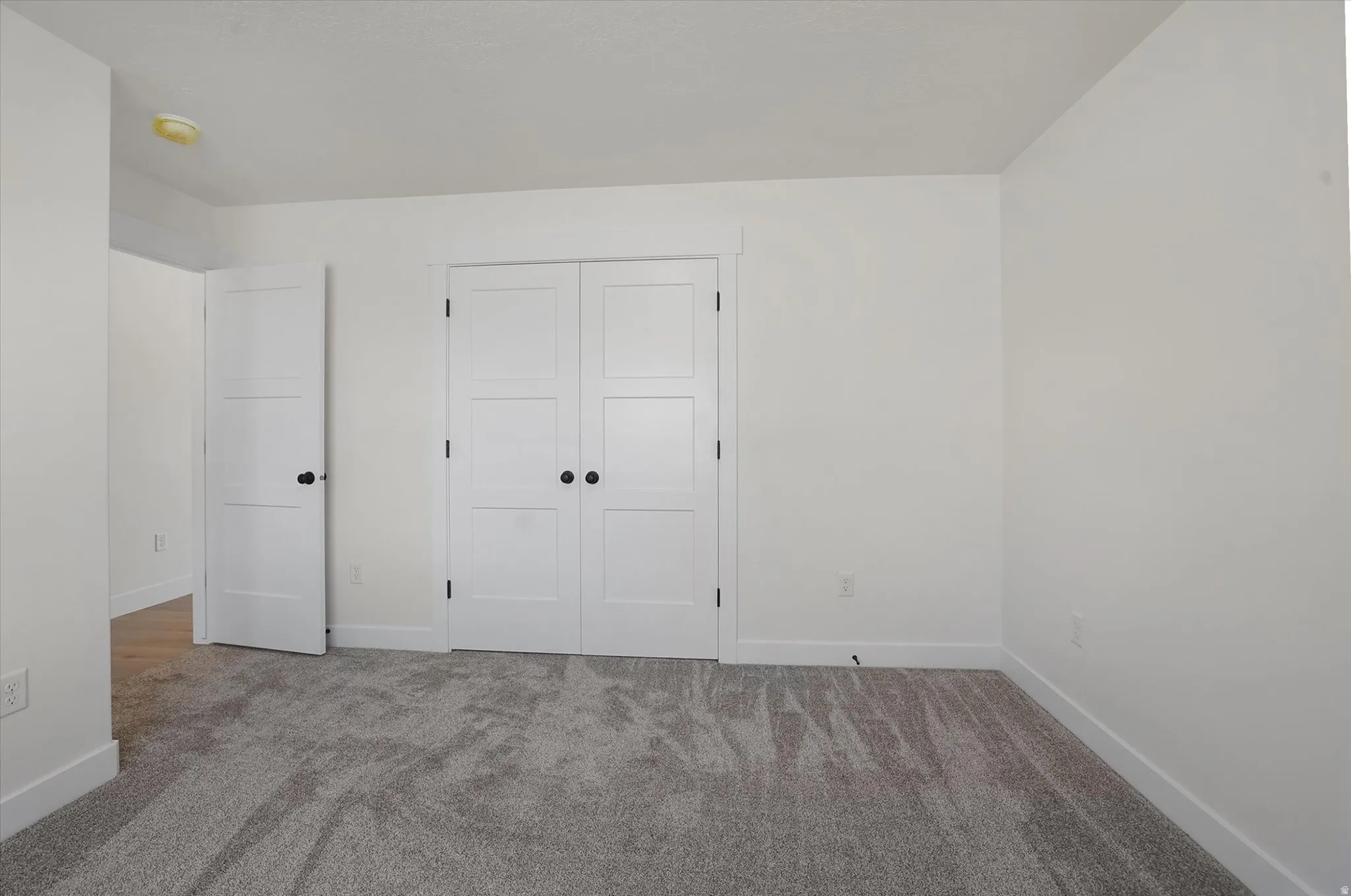 Carpeted interior space featuring white walls and white baseboards
