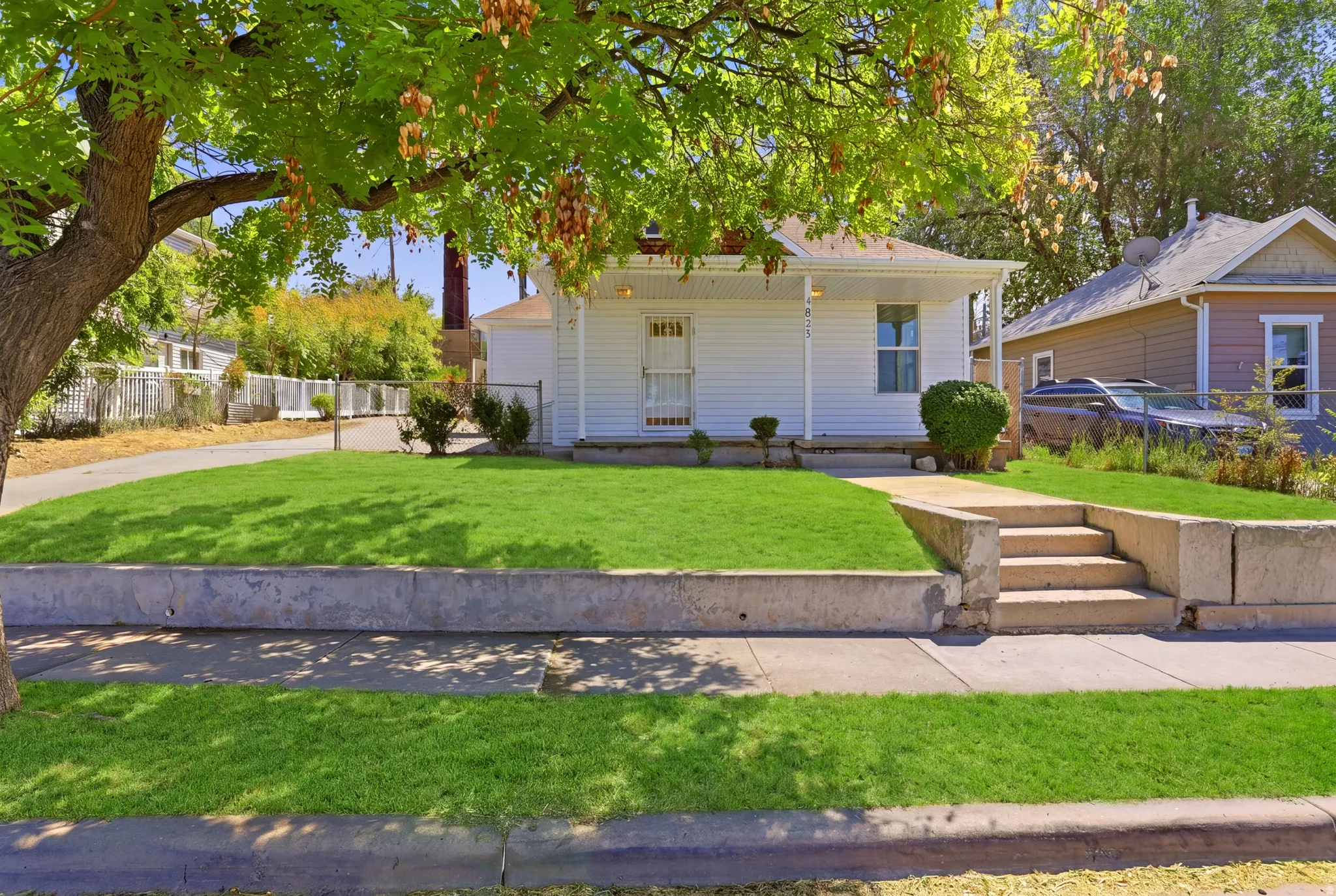 White exterior residence with a covered front porch and a prominent mature tree