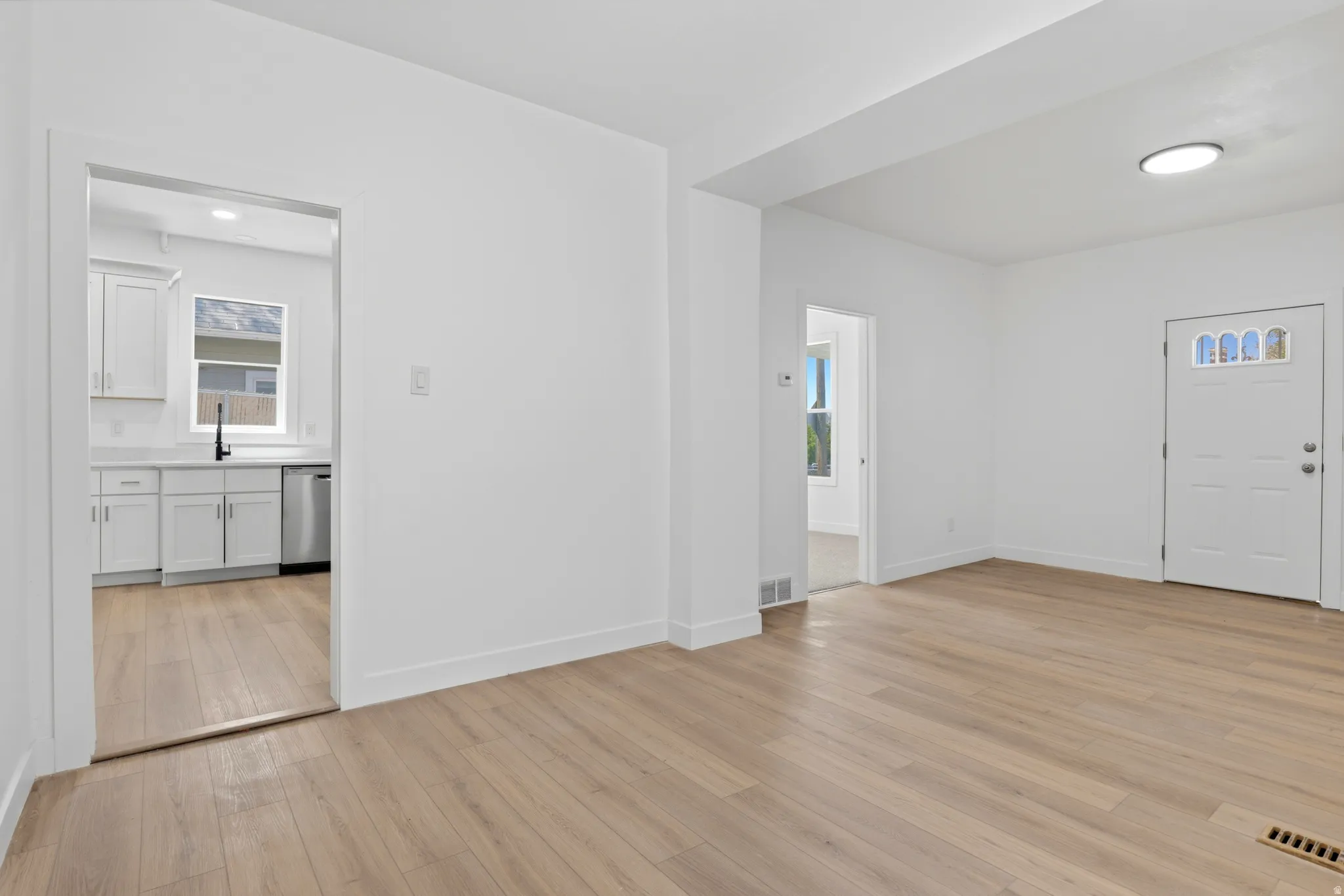 Open concept living space featuring light wood-finish flooring, white baseboards, and bright white walls