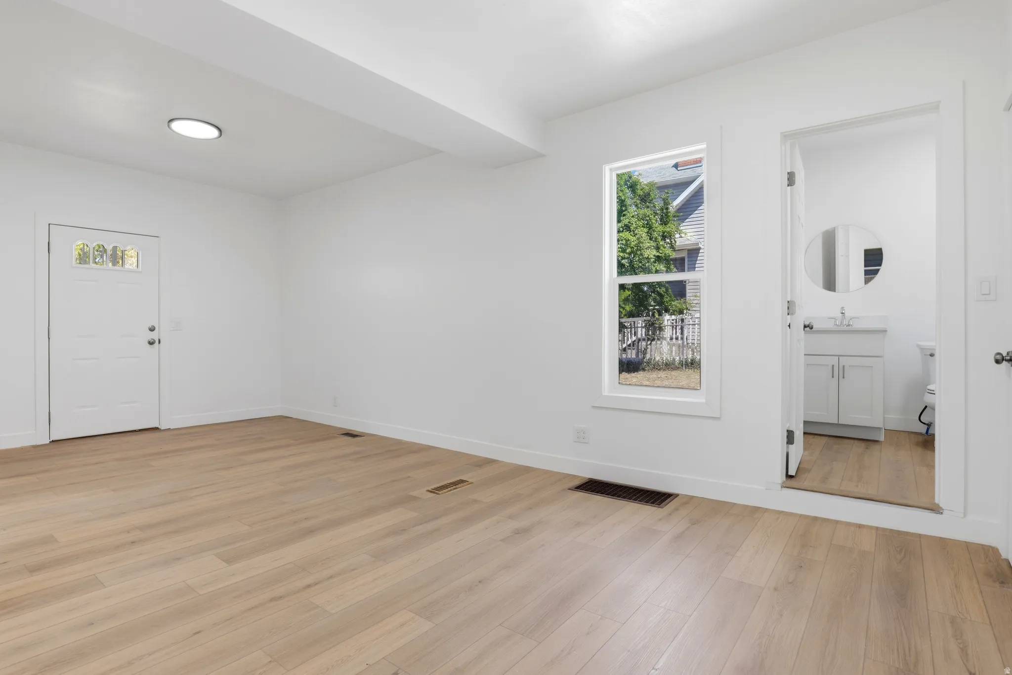 Spacious room featuring light wood-finish flooring, white walls, and a recessed ceiling light