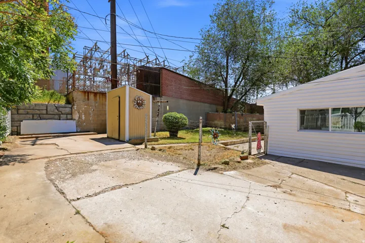 Concrete patio area with a detached storage shed and a retaining wall