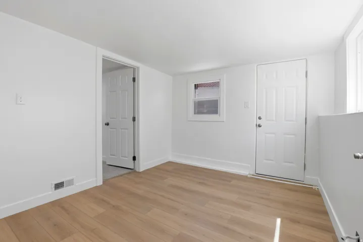 Bright interior space featuring light wood-finish flooring, white walls, and white trim