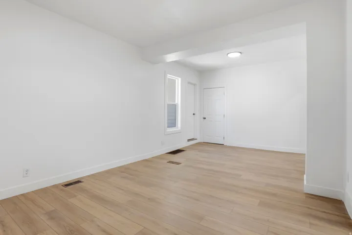 Spacious room featuring wood-finish flooring, white baseboards, and a neutral wall palette