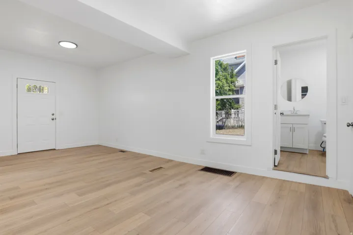 Spacious room featuring light wood-finish flooring, white walls, and a recessed ceiling light