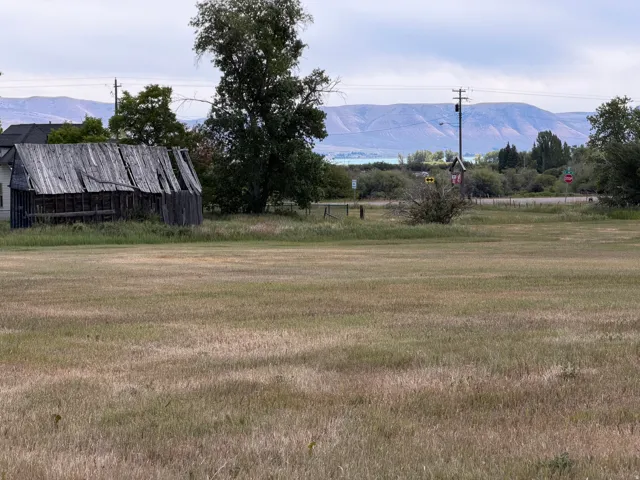 Expansive open field with distant mountains and a serene body of water forming a scenic backdrop