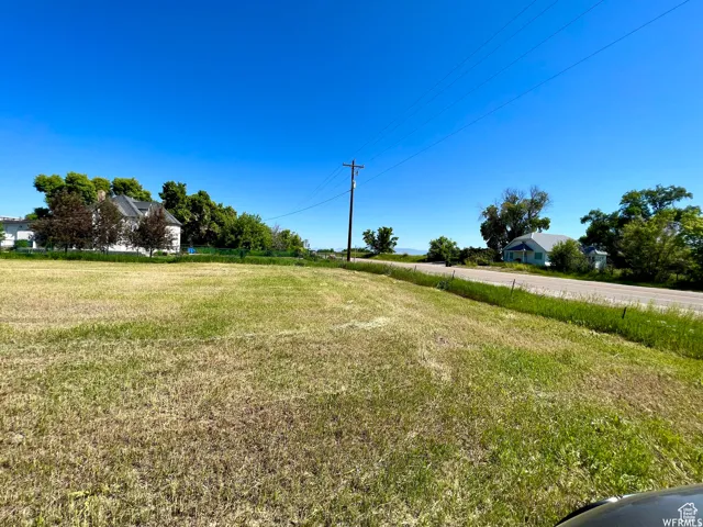 Expansive open land featuring a clear perimeter, adjacent roadway, and distant residential structures