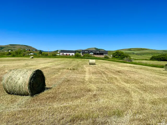 Expansive rural landscape featuring a harvested field and rolling green hills