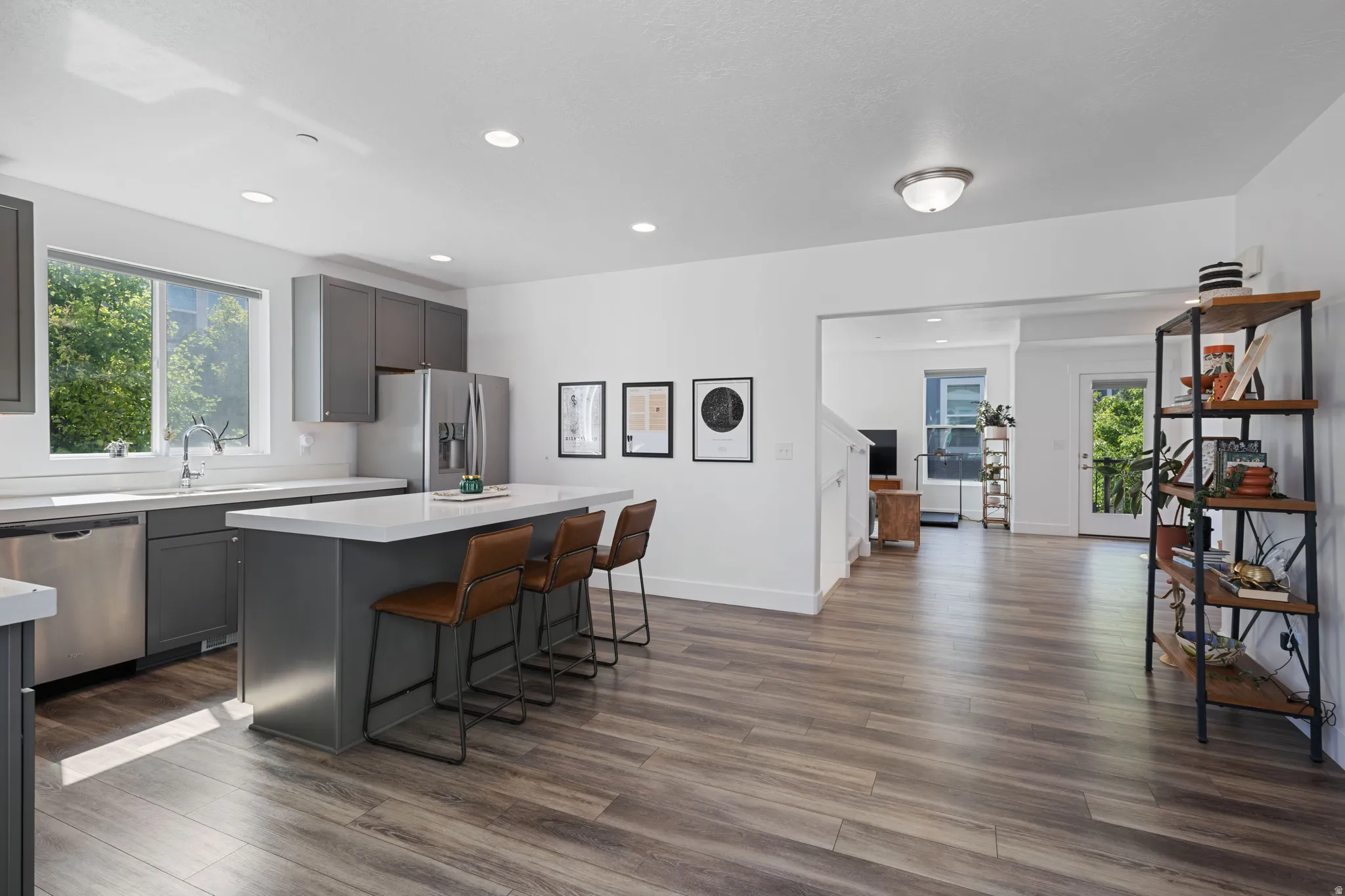 Modern kitchen featuring stainless steel appliances, dark gray cabinetry, and a center island with a light-toned countertop