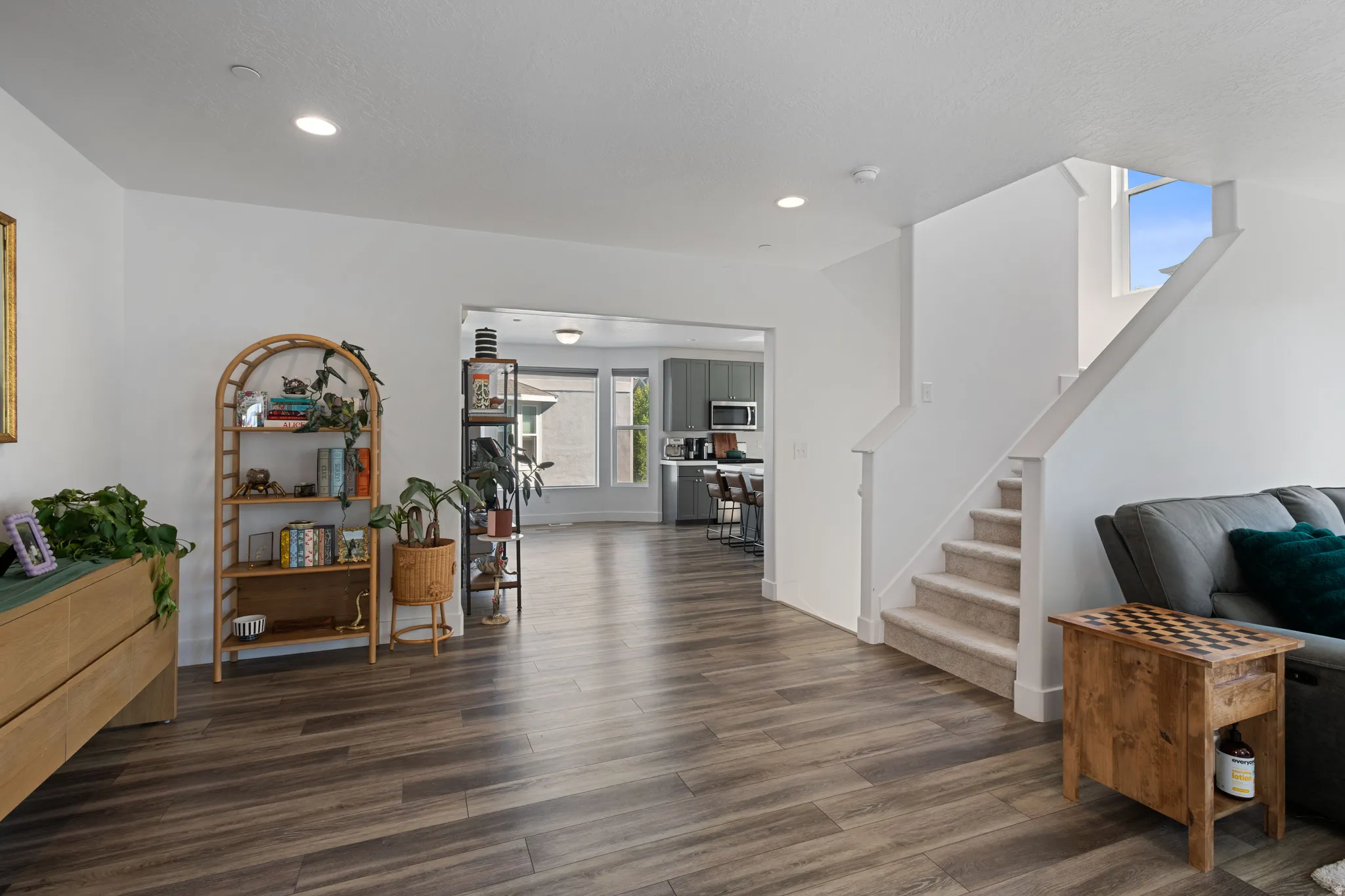 Open-concept interior featuring wood-finish flooring, recessed lighting, and a staircase with carpeted treads