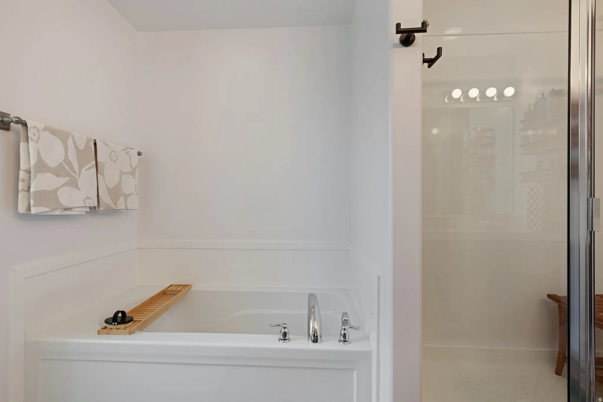 Built-in soaking tub with chrome fixtures complemented by a clear glass-enclosed shower with a multi-bulb light fixture