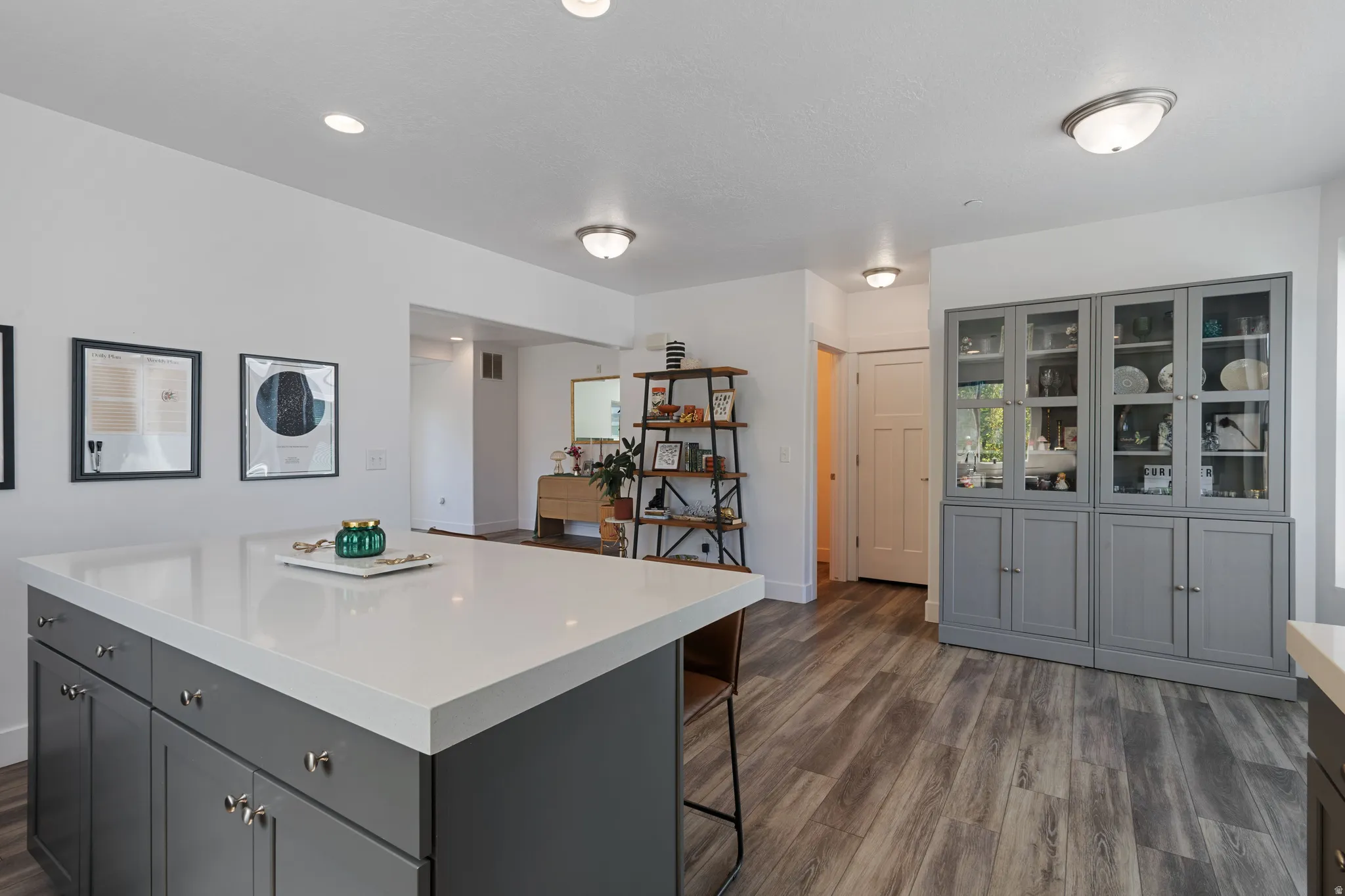 Spacious open-concept living area featuring an expansive kitchen island with a light-toned countertop, ample gray cabinetry, and recessed lighting