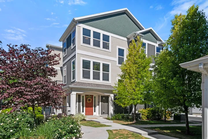 Modern townhome exterior featuring multi-toned siding, a distinctive red entry door, and a covered porch