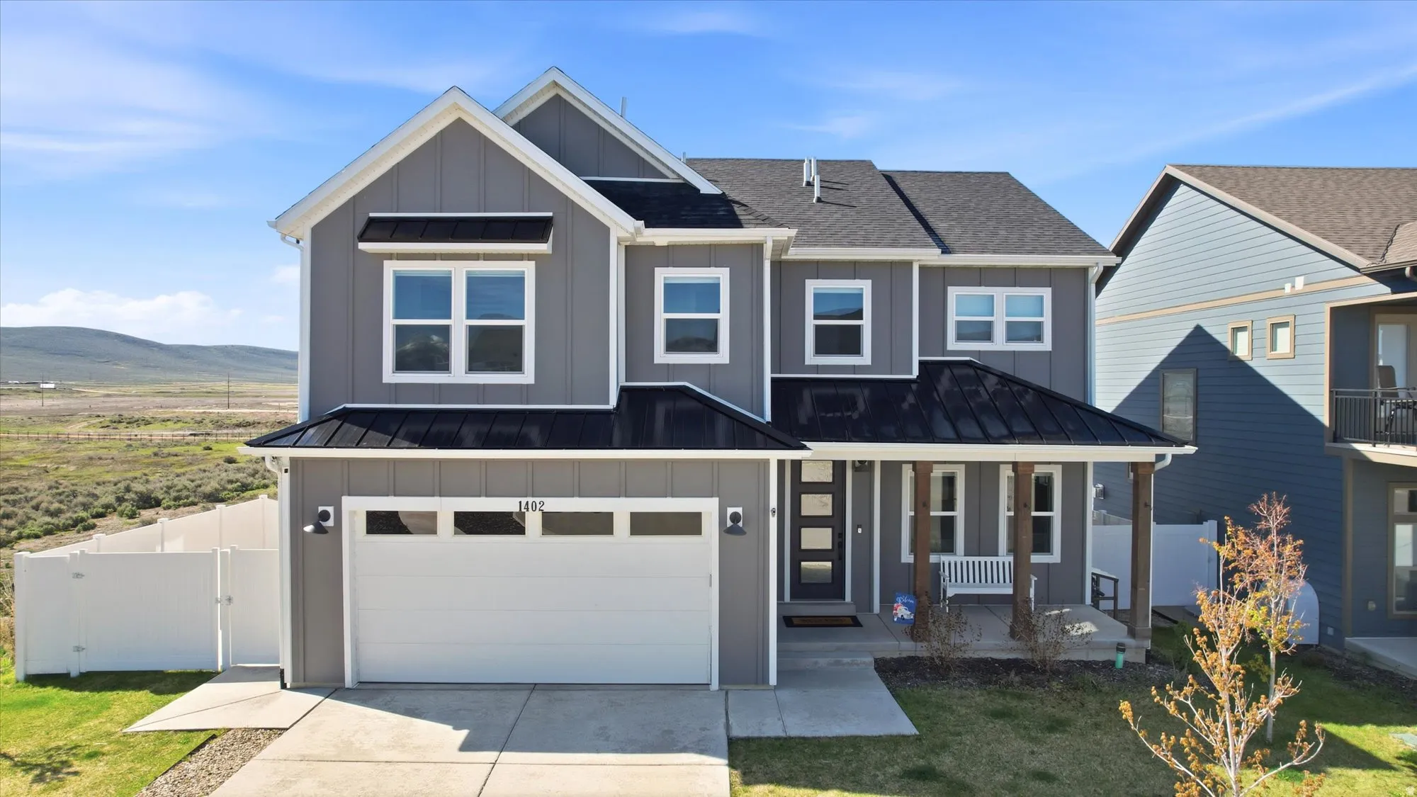 Contemporary two-story residence featuring grey siding and a dark shingle roof